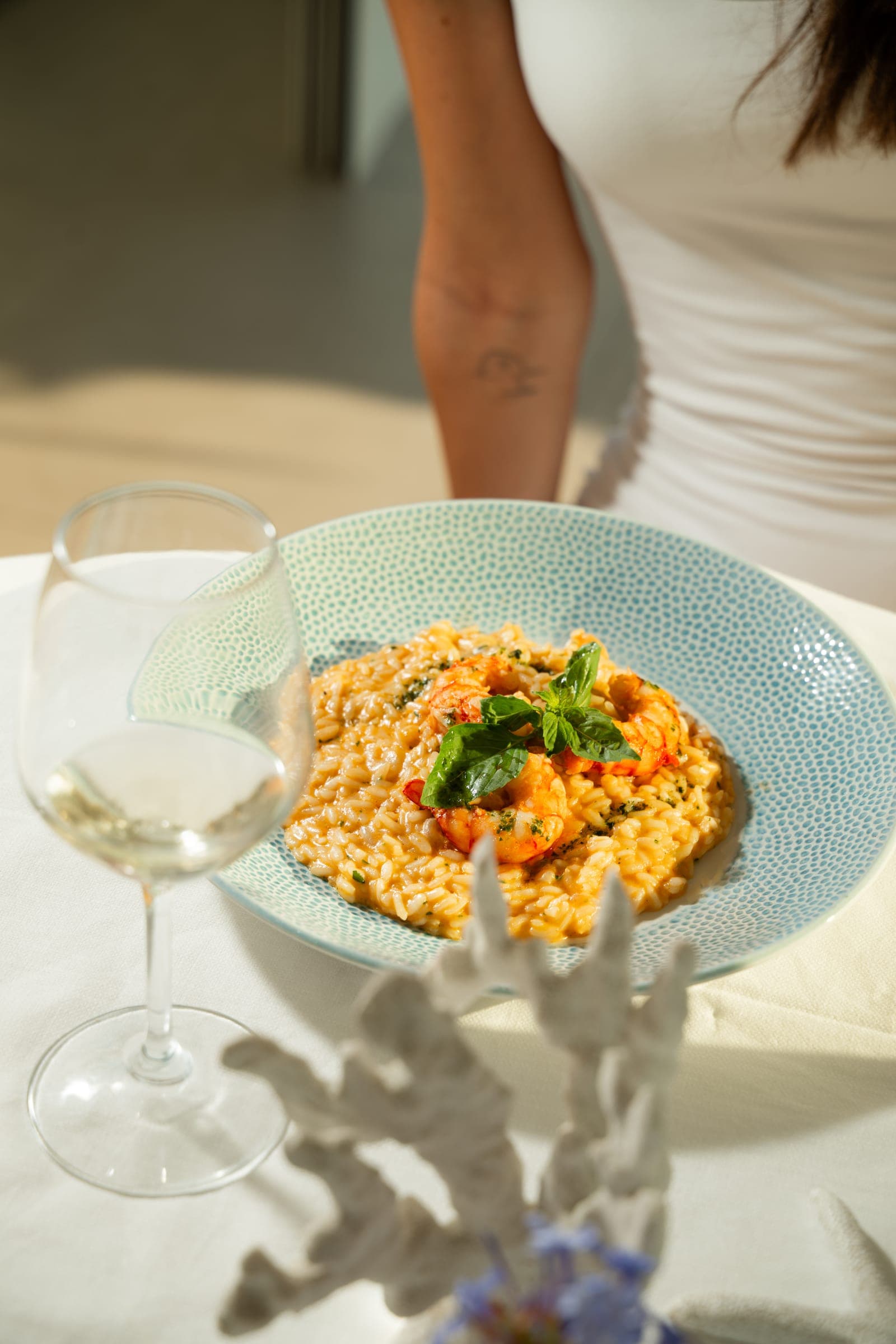Un primo di mare servito con un calice di vino al tavolo fronte mare